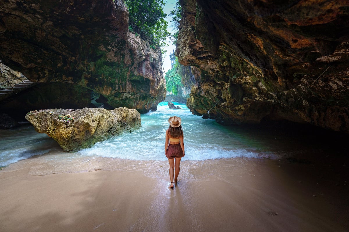 Viajera con sombrero contemplando el mar desde las rocas al atardecer